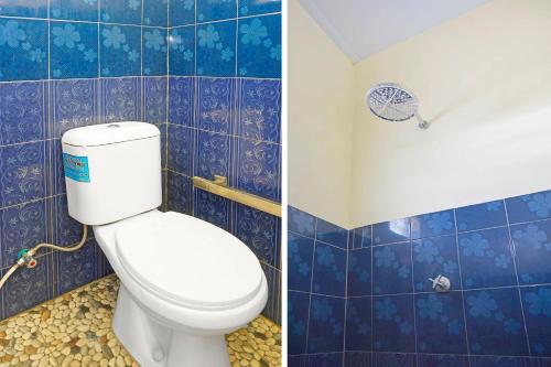 uma casa de banho com WC e uma parede de azulejos azuis em OYO 91411 Putih Mulia Homestay Syariah em Lumajang