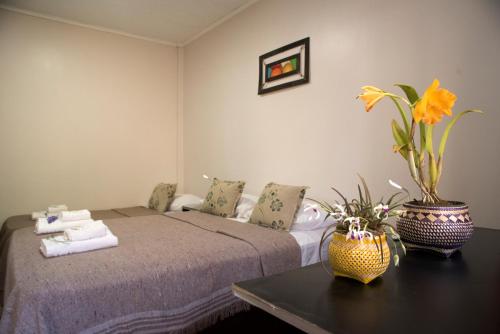 ein Schlafzimmer mit einem Bett und einem Tisch mit Blumen darauf in der Unterkunft Posada Yvoty in Puerto Iguazú