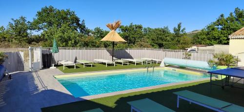 a swimming pool with chairs and an umbrella in a backyard at Gites de la Casasole in Vogüé