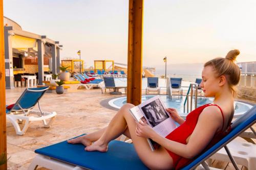 a woman sitting on a bench reading a magazine at Crowne Plaza Jordan Dead Sea Resort & Spa, an IHG Hotel in Sowayma