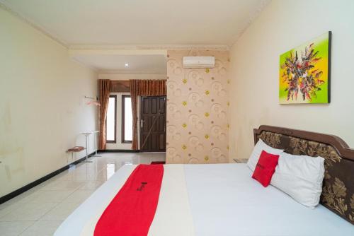 una camera da letto con un letto con una coperta rossa sopra di RedDoorz At Jalan Bukit Keminting a Palangkaraya