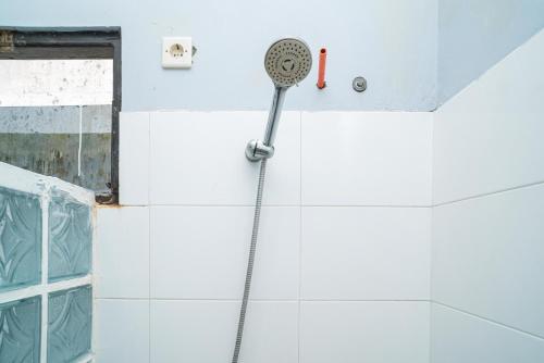 a shower in a bathroom with a shower head at RedDoorz @ Wisma Pangrango in Palangkaraya