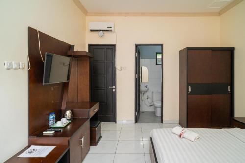 a room with a bed and a tv and a bathroom at RedDoorz @ Wisma Pangrango in Palangkaraya
