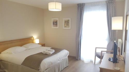 a bedroom with a bed with a television and a window at Résidence Séniors Domitys Les Hautes Feuilles in Reims