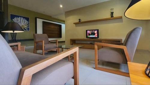 a living room with a table and chairs and a television at Gold Coast Morib Studio l Apartment I Penthouse in Banting