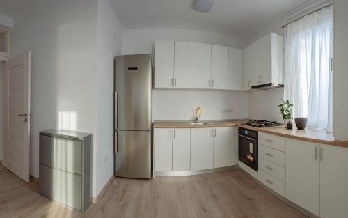 a kitchen with white cabinets and a stainless steel refrigerator at Solomon Apartments Ap 3 in Sângeorgiu de Mureș