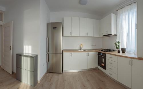 a kitchen with white cabinets and a stainless steel refrigerator at Solomon Apartments Ap 3 in Sîngeorgiu de Mureş