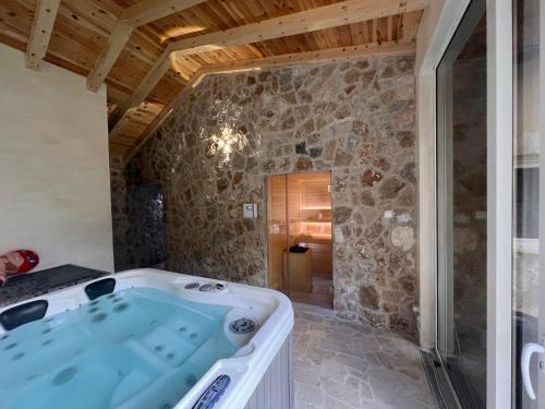 eine Whirlpool-Badewanne in einem Zimmer mit einer Steinmauer in der Unterkunft Family SPA Apartments Sunny&Shiny in Šavnik