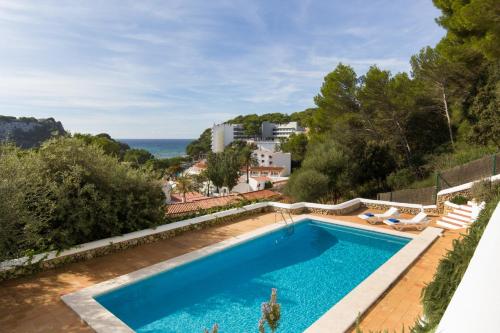 a swimming pool with a view of the ocean at Apartamentos Encanto Del Mar in Cala Galdana