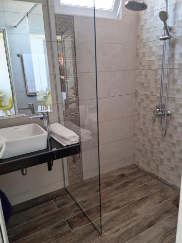 a bathroom with a shower and a sink and a mirror at Vromos Guest Rooms in Chernomorets