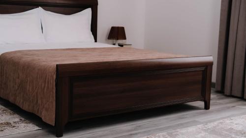 a bedroom with a large bed with a wooden headboard at Апарт отель Welcome in Taldykorgan