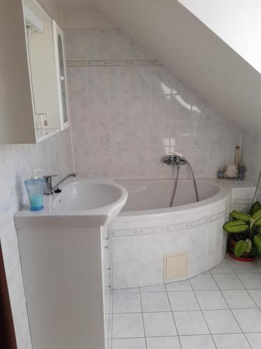 a white bathroom with a tub and a sink at Apartmán v rodinném domě in Dětenice