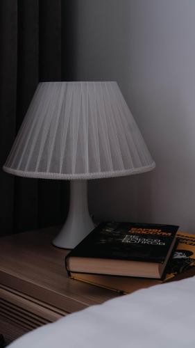 a lamp sitting on top of a table with a book at Апарт отель Welcome in Taldykorgan