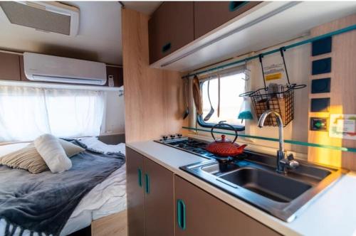 a kitchen in a caravan with a sink and a bed at השקדיה - Shkedya in Mitzpe Ramon