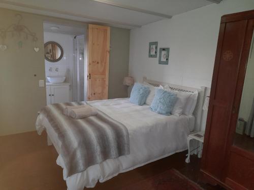 a bedroom with a large white bed with blue pillows at Little Camelot in Langebaan