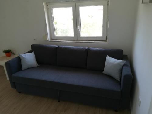 a blue couch in a room with two windows at Summer cottage with breathtaking view in Zečevo Rogozničko