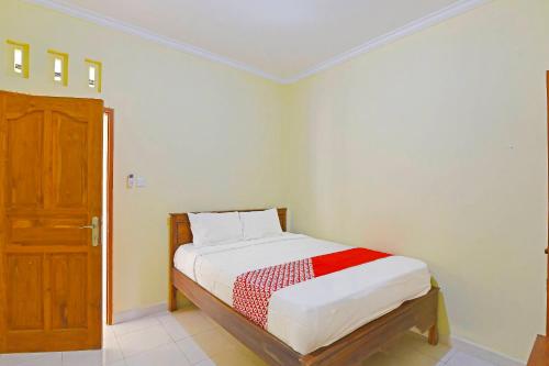 ein kleines Schlafzimmer mit einem Bett und einer Holztür in der Unterkunft OYO Life 90675 Ld Residence in Ungasan