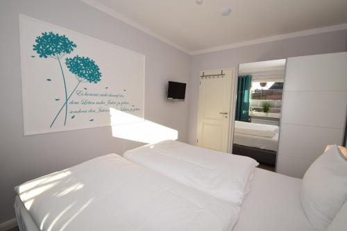 a white bedroom with a bed and a mirror at Ferienwohnung Whg.3 im Haus Sarah in Büsum