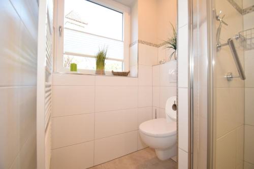 a white bathroom with a toilet and a window at Ferienwohnung Whg.3 im Haus Sarah in Büsum