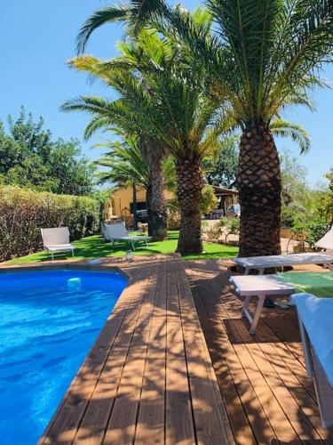 een zwembad met twee palmbomen en een tafel bij Casa vacanze La Posada in Partanna