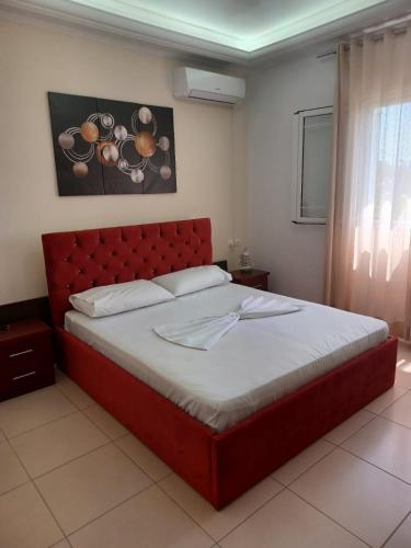 a bed with a red headboard in a bedroom at Apartamente Gleni in Sarandë