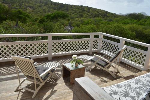 a deck with two chairs and a table and a white fence at Don Genaro Apartments in Barber