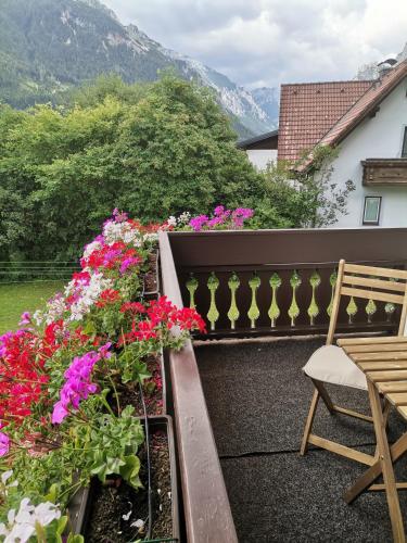 a balcony with flowers and a wooden chair at Haus Bergblick am Grünen See in Oberort