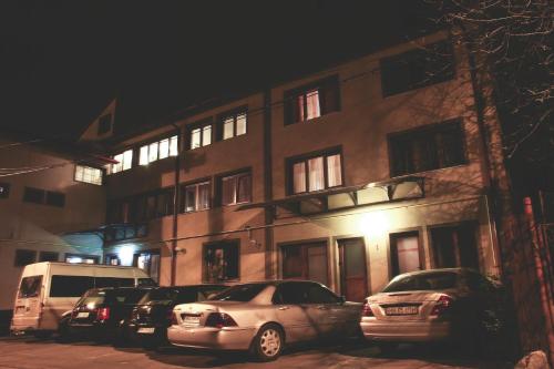 two cars parked in front of a building at night at Pensiunea Pictorilor in Baia Mare