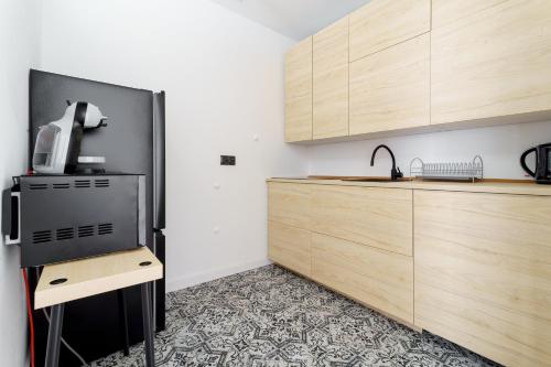 cocina con nevera negra y armarios de madera en APARTAMENT SŁONECZNY, en Chełmno