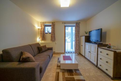a living room with a couch and a tv at Penzion Sagan in Terchová
