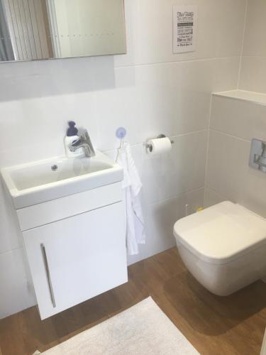 Baño blanco con lavabo y aseo en Hedlea en Redruth