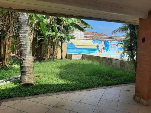 a mural on a wall in a yard with a tree at Hostel Ohana Beach in Mongaguá