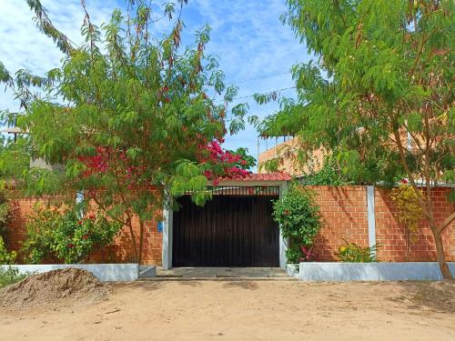 a gate in a brick wall with a tree and flowers at Bijao Hostel in Tarapoto