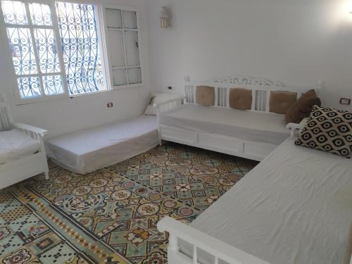 um quarto branco com 2 camas e uma janela em Dar Fatma em Hammamet