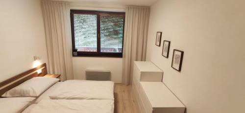 Habitación pequeña con 2 camas y ventana en Apartmán Chopok Juh Relax & Enjoy, en Tale