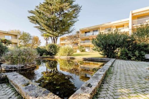 une cour avec un étang en face d'un bâtiment dans l'établissement Hello Côte d'Azur - Spacieux 2 pièces au calme à 5 min des plages, à Antibes