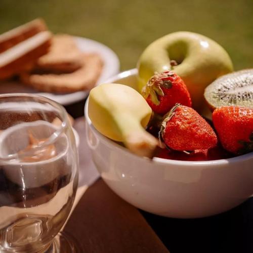 a bowl of fruit on a table next to a glass of wine at Cabañas Valle de los Ciervos in Tandil