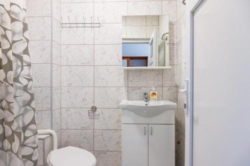 a white bathroom with a sink and a toilet at Vila Peristeron in Golubac