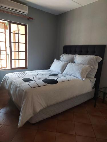 een slaapkamer met een groot bed met witte lakens en kussens bij Pendleberry Holiday Resort - Unit 40 in Bela-Bela