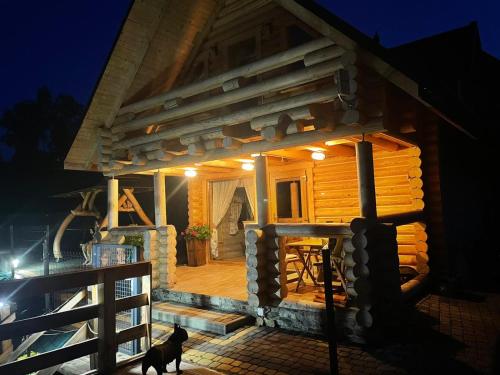 a small wooden cabin with a deck at night at Domek Nad River San - pierwsza linia brzegowa - balia - łodzie - basen in Olchowiec
