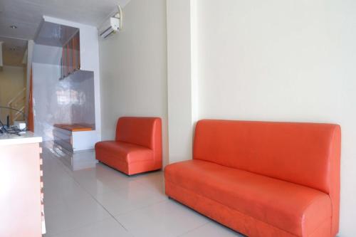 two orange chairs sitting in a room with a wall at RedDoorz Syariah at Kelud Sampangan Semarang in Jomblang