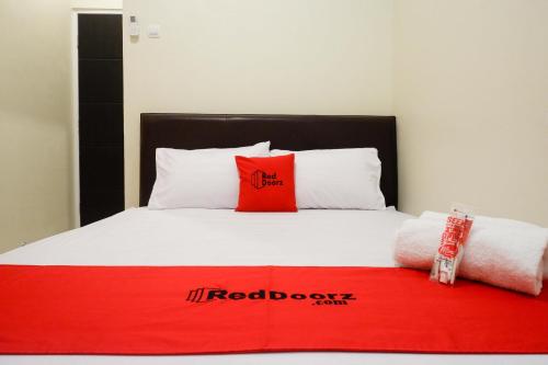 a bed with a red board on it with two pillows at RedDoorz Syariah at Kelud Sampangan Semarang in Jomblang
