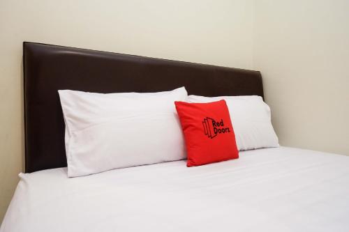 uma cama com duas almofadas brancas e uma almofada vermelha em RedDoorz Syariah at Kelud Sampangan Semarang em Jomblang
