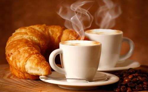 two cups of coffee and a croissant and coffee beans at King House B&B Catania in Catania
