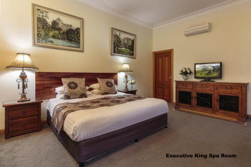 een slaapkamer met een groot bed en 2 nachtkastjes bij Mt Tamborine Stonehaven Boutique Hotel in Mount Tamborine