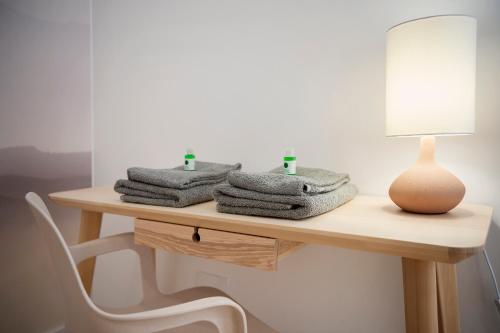 a table with towels on it with a lamp and a chair at Magnifique appartement plein centre, calme, Netflix in Mirepoix