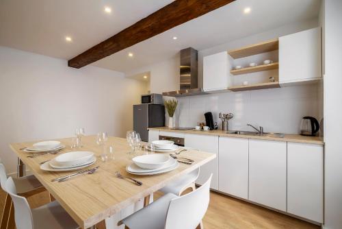 eine Küche mit einem Holztisch und weißen Schränken in der Unterkunft Magnifique appartement plein centre, calme, Netflix in Mirepoix