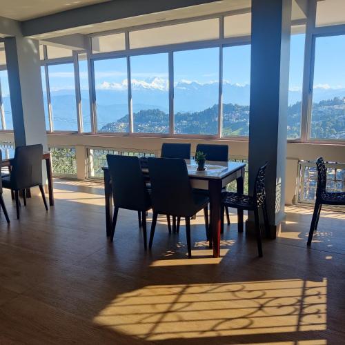 a dining room with a table and chairs and windows at The Silver Spring Homestay in Darjeeling
