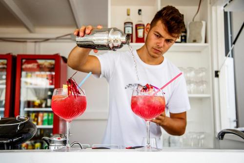 Un homme fait une boisson dans deux verres dans l'établissement Hotel Carillon, à Baveno