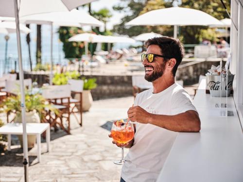 a man holding a drink in a glass at Hotel Carillon in Baveno